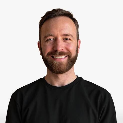 Nathan Fields, a white male in his thirties with brown hair and a full brown beard wearing a darker shirt and smiling.