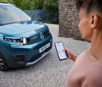 Woman with a smartphone in front of New ë-Berlingo