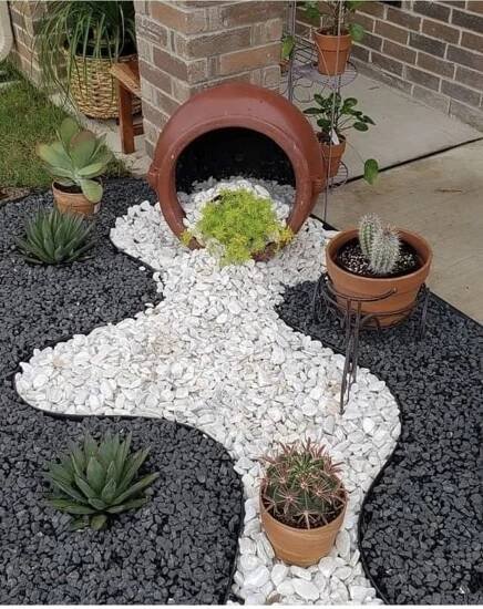 there are many potted plants on the ground in front of this house, including succulents and cacti