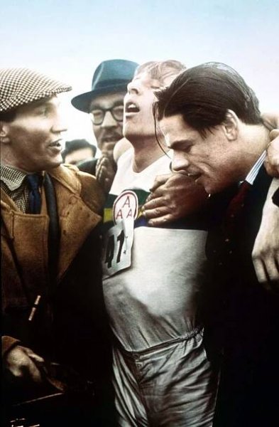 An exhausted Roger Bannister is held aloft at the finish line.