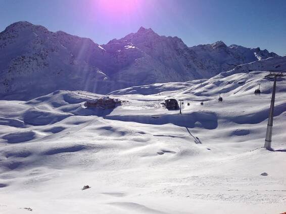 the sun shines brightly on snow covered mountains and ski lifts in the foreground