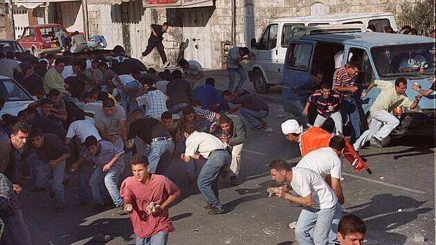 Palestinci házejí kameny na izraelskou pořádkovou policii v Jeruzalémě během střetů, které vypukly 29. září 2000 po pátečních modlitbách v komplexu mešity Al-Aksá ve Starém městě Jeruzaléma. Pět Palestinců bylo zabito a více než dvě stě zraněno během druhého dne násilností, které následovaly po návštěvě izraelského pravicového opozičního vůdce Ariela Šarona v komplexu mešity, jež je třetí nejsvatější svatyní islámu.