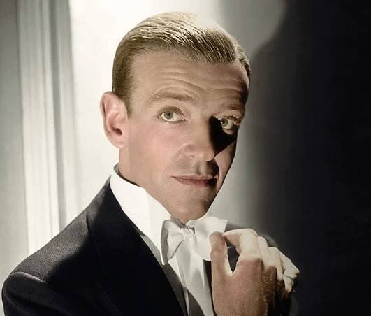 Fred Astaire in black suit is looking at camera.