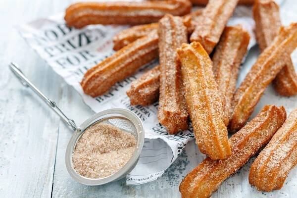 Pile of fresh churros pastries with cinnamon and sugar.