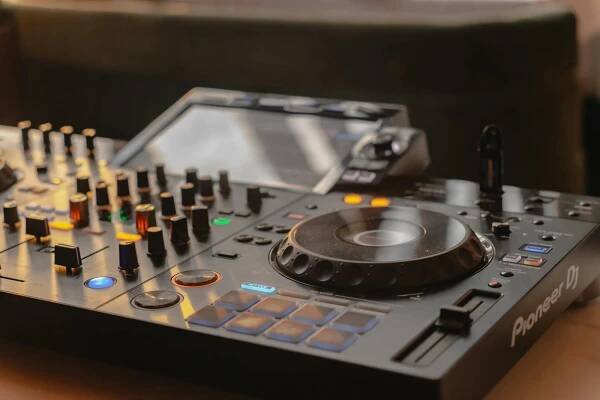 Free Close-up view of a modern DJ mixer with knobs, sliders, and lights, ideal for music production. Stock Photo