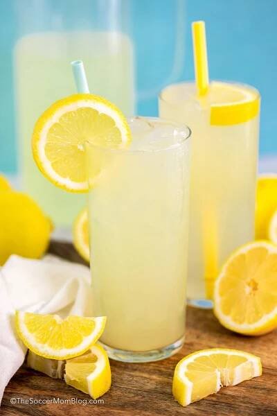 two tall glasses of homemade lemonade, with pitcher behind them.