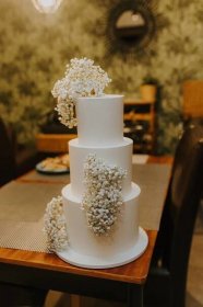 Bezplatný obrázek: Krásný elegantní bílý svatební dort na stole v restauraci