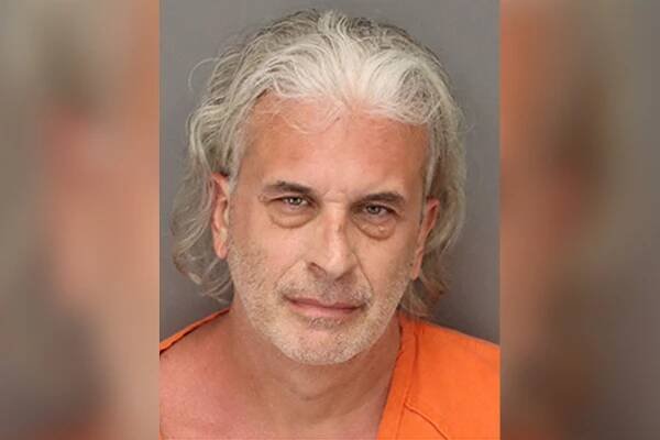 Ronald Antinore in orange jumpsuit in mugshot.