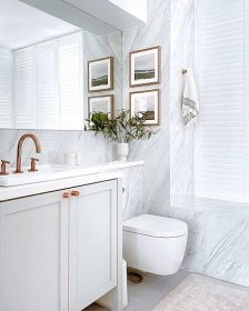 Bright white bathroom with built-in shuttered window treatment for privacy.