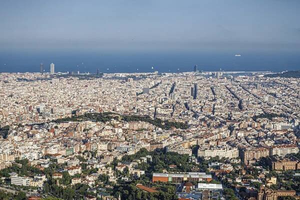 A panoramic view of Barcelona from Collserola mountain with views to the Eixample neighborhood, the Mediterranean Sea, and the Hotel Arts and Mapfre towers