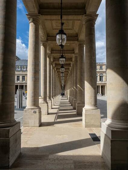 bezplatná Elegantní kamenné sloupy Palais Royal v Paříži, vrhající dramatické stíny pod modrou oblohou. Základová fotografie