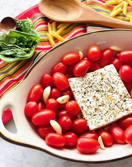 garlic cloves tucked into tomatoes surrounding feta cheese.