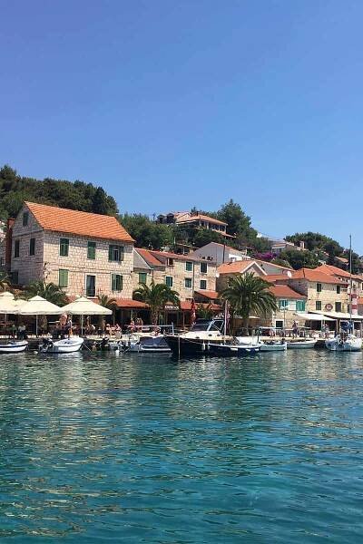 A view of the tiny fishing village of Maslinica on the island of Solta taken from a boat as it approaches the shore on a sunny day.
