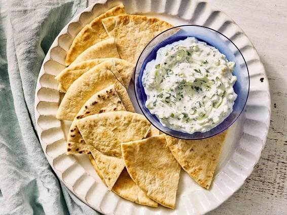 Bowl of tzatziki dip served with warm pita wedges.