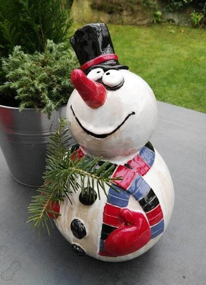 a snowman statue sitting next to a potted plant