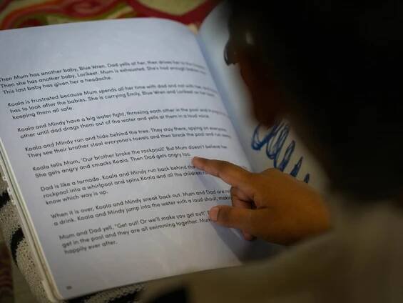A person pointing to a passage in a children's book