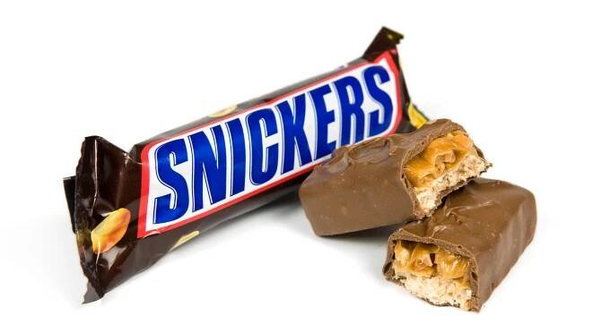 Snickers chocolate bar unwrapped and broken in two.