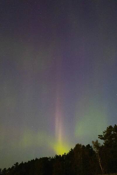 Green, orange, and purple streaks of light in the sky due to aurora borealis.
