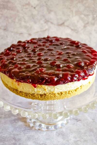 Philadelphia No Bake Cheesecake With Berries sitting on a glass cake support.