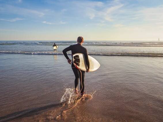 Man with a surf board at the Carcavelos Beach