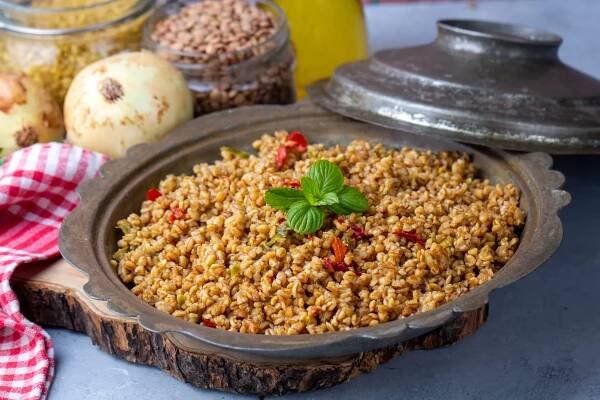 A concrete table showing a portion of bulgur pilaf and some of its ingredients. 
