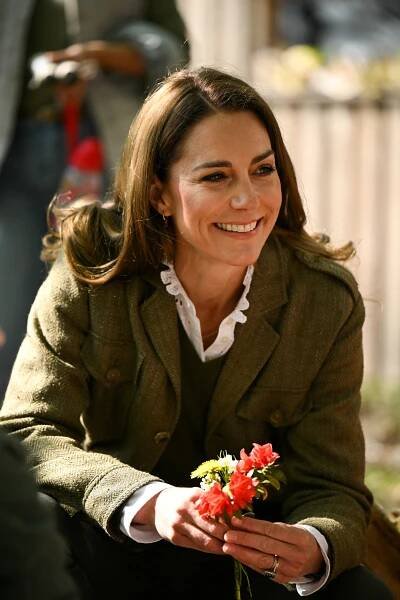 Catherine, Princess of Wales, smiling and holding flowers.