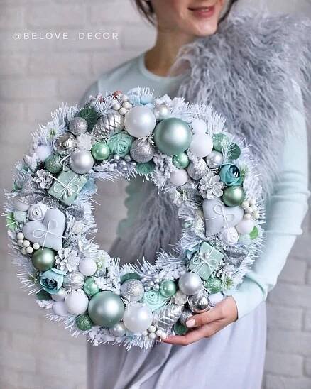 a woman holding a wreath with ornaments on it