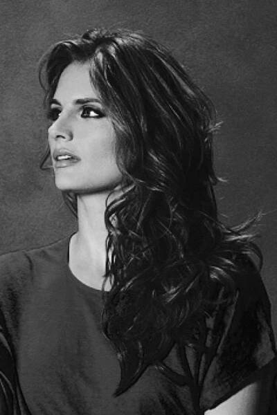 a black and white photo of a woman with her hair blowing in the wind, looking off to the side