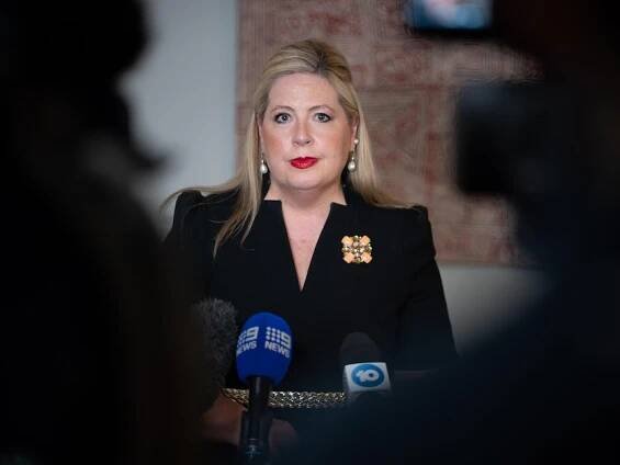 Woman with blonde hair talking to media. 