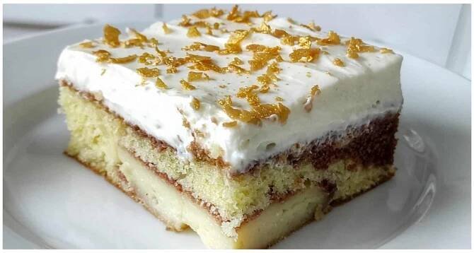 a piece of cake with white frosting and orange zest on top sitting on a plate