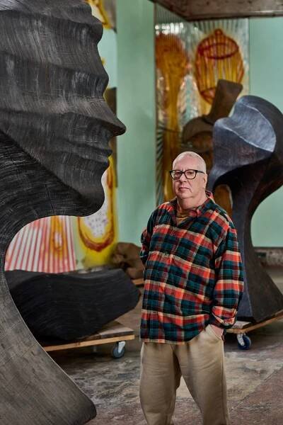Portrait of artist Ray Smith in his Brooklyn studio with two large totemic sculptural works made of laminated burnt plywood