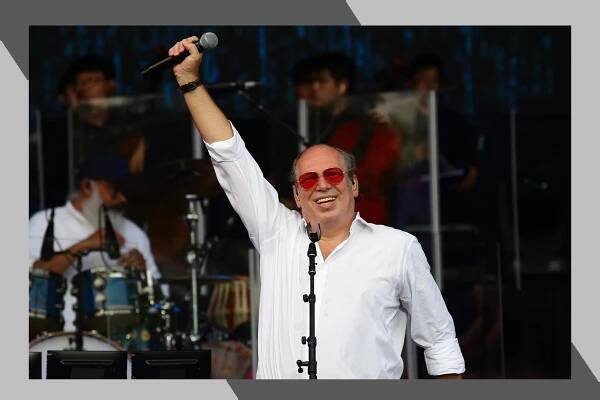 Hans Zimmer triumphantly raises his microphone in concert.