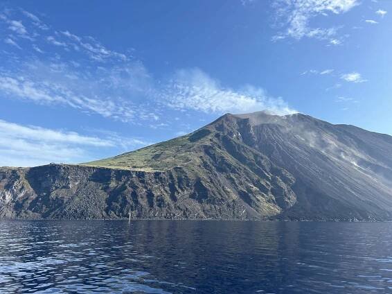 Sopka Stromboli s modrou oblohou a klidným mořem.