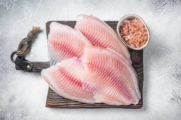 čerstvé tilapia bílé rybí filé v dřevěném podnosu. černé pozadí. pohled shora - tilapie - stock snímky, obrázky a fotky