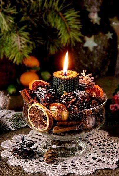 a candle is lit in a glass bowl filled with dried fruit and pineconis
