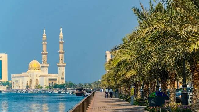 view of riverside promenade in Sharjah with Al Maghfirah mosque at background UAE