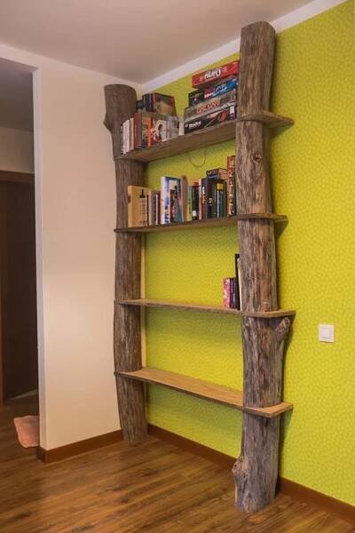 a bookshelf made out of logs in the corner of a room with yellow walls