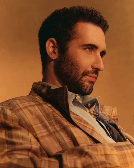 Jordan Firstman looking off camera in a plaid jacket