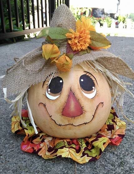 a pumpkin with a scarecrow's hat and leaves on it sitting on the ground