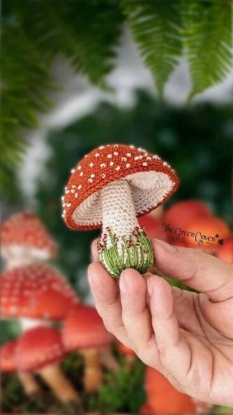 a hand is holding a tiny red mushroom