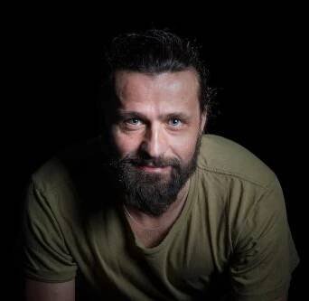Pavel Zavadil na portrétní fotografii na černém pozadí.