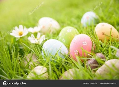 Stáhnout - Veselé Velikonoce! Detailní barevné velikonoční vejce v hnízdě na zelené trávě pole během západu slunce pozadí. — Stock obrázek