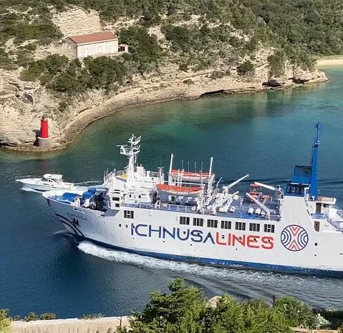 Un traghetto Ichnusa Lines in navigazione con uno sfondo verde e roccioso