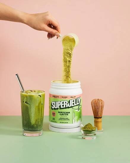 A glass of green smoothie with a spoon in it.