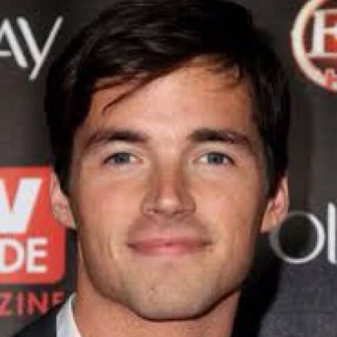 a close up of a person wearing a suit and tie with a smile on his face