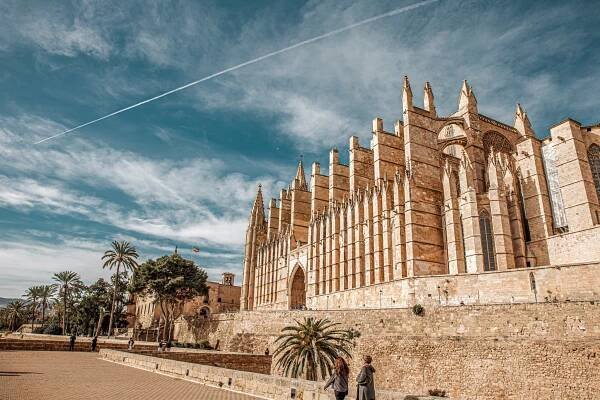The side view of Palma Cathedral with its iconic thick buttresses against a blue sky