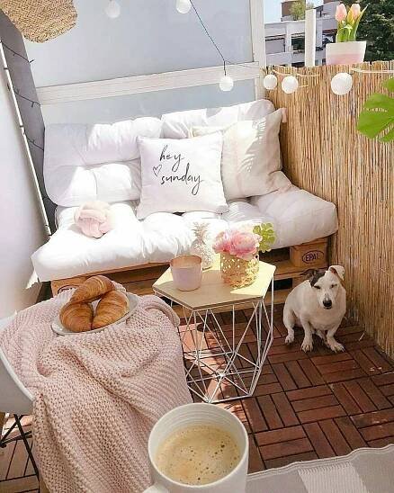 a white couch sitting on top of a wooden floor next to a cup of coffee