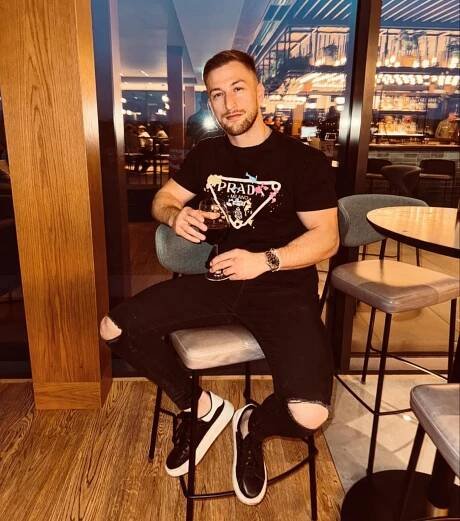 Man sitting at a bar, holding a glass of wine.
