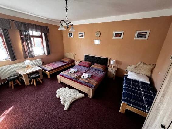 a living room with two beds and a table at Restaurace a penzion Vlčí jáma in Horní Blatná