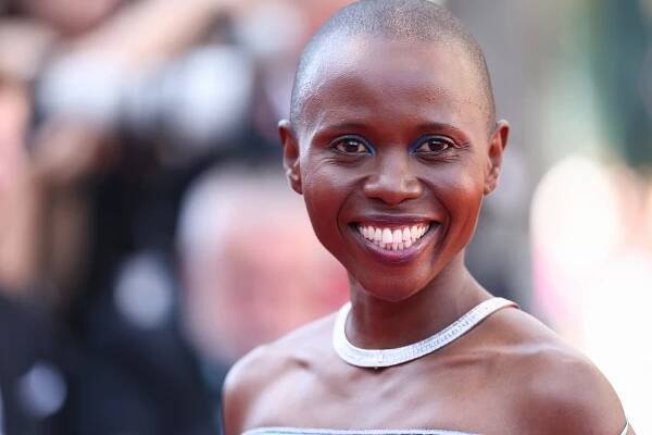 Eliane Umuhire smiling on the red carpet, wearing a sleeveless dress